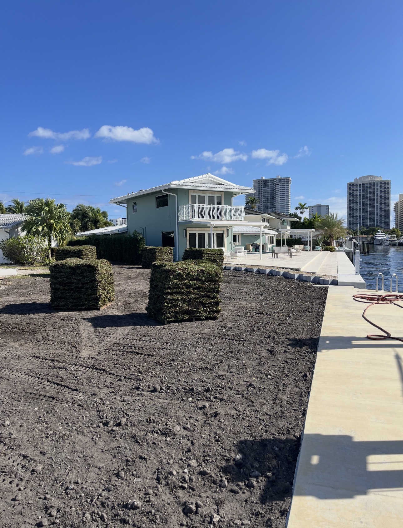 Waterfront yard graded and prepared with pallets of sod ready for installation