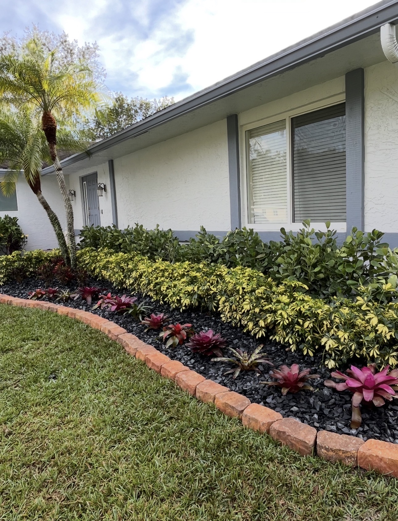 Same front yard landscape bed after refresh with colorful planting and defined border