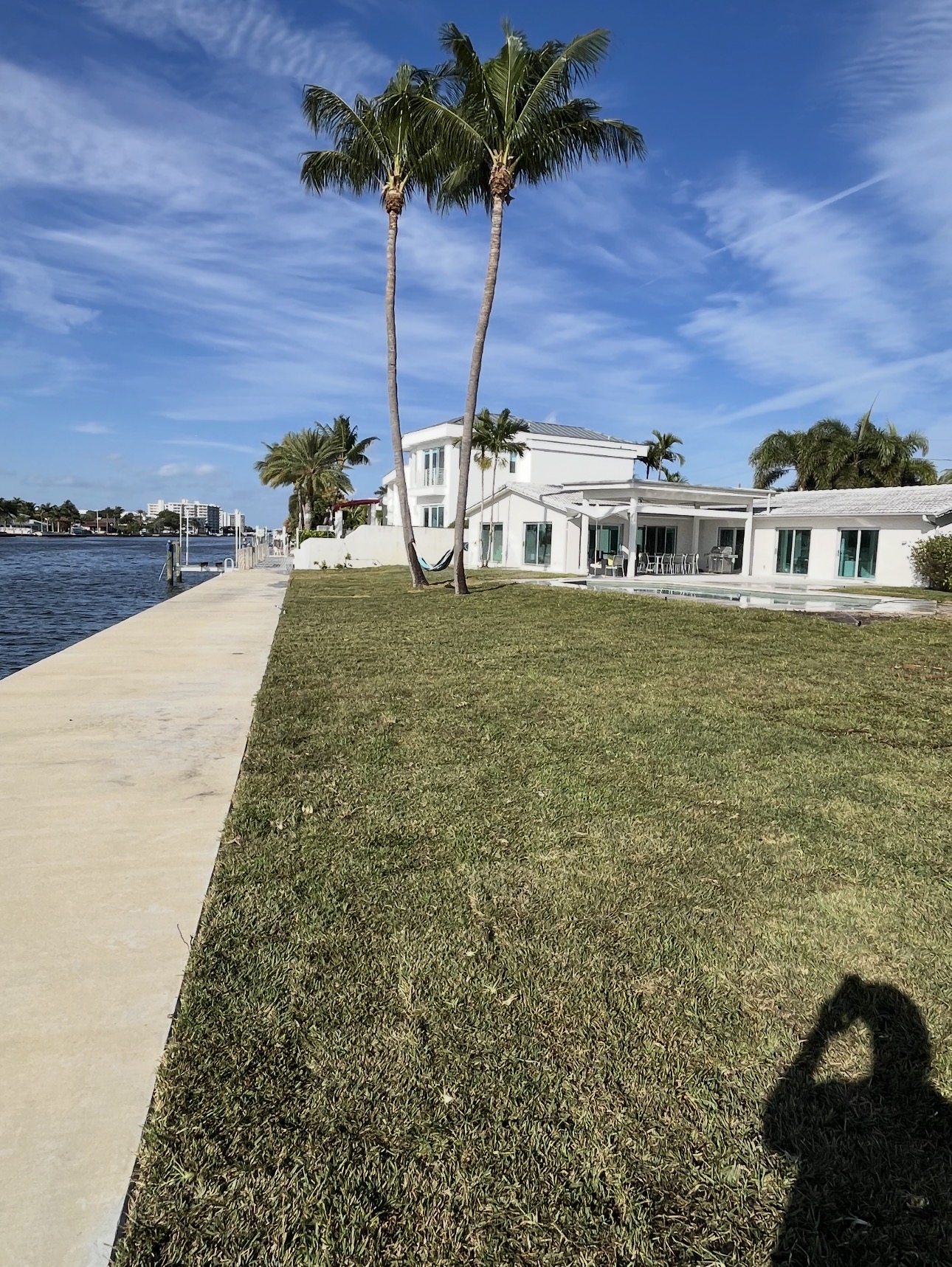 New sod lawn along the waterfront viewed from the opposite angle with palms and dock
