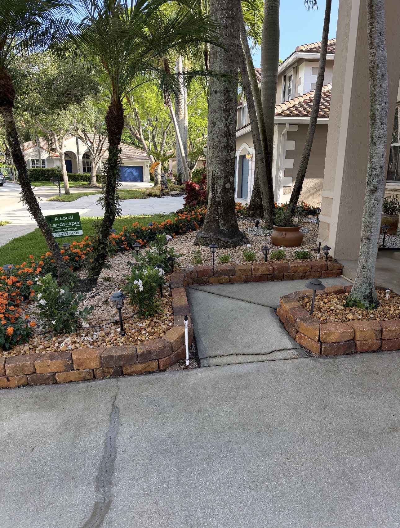 Same front entry after redesign with new beds, stone, plantings, and lighting